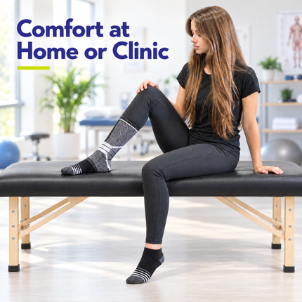 Woman wearing the Healthy You ankle compression sleeve seated on a treatment table in a clinic