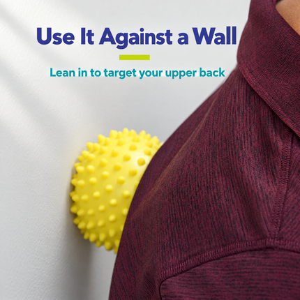 Using a spiky massage ball against a wall on the upper back